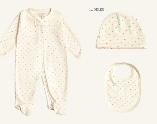 A set of three baby items including a beige colored onesie with hearts, a matching beige hat with hearts, and a beige bib